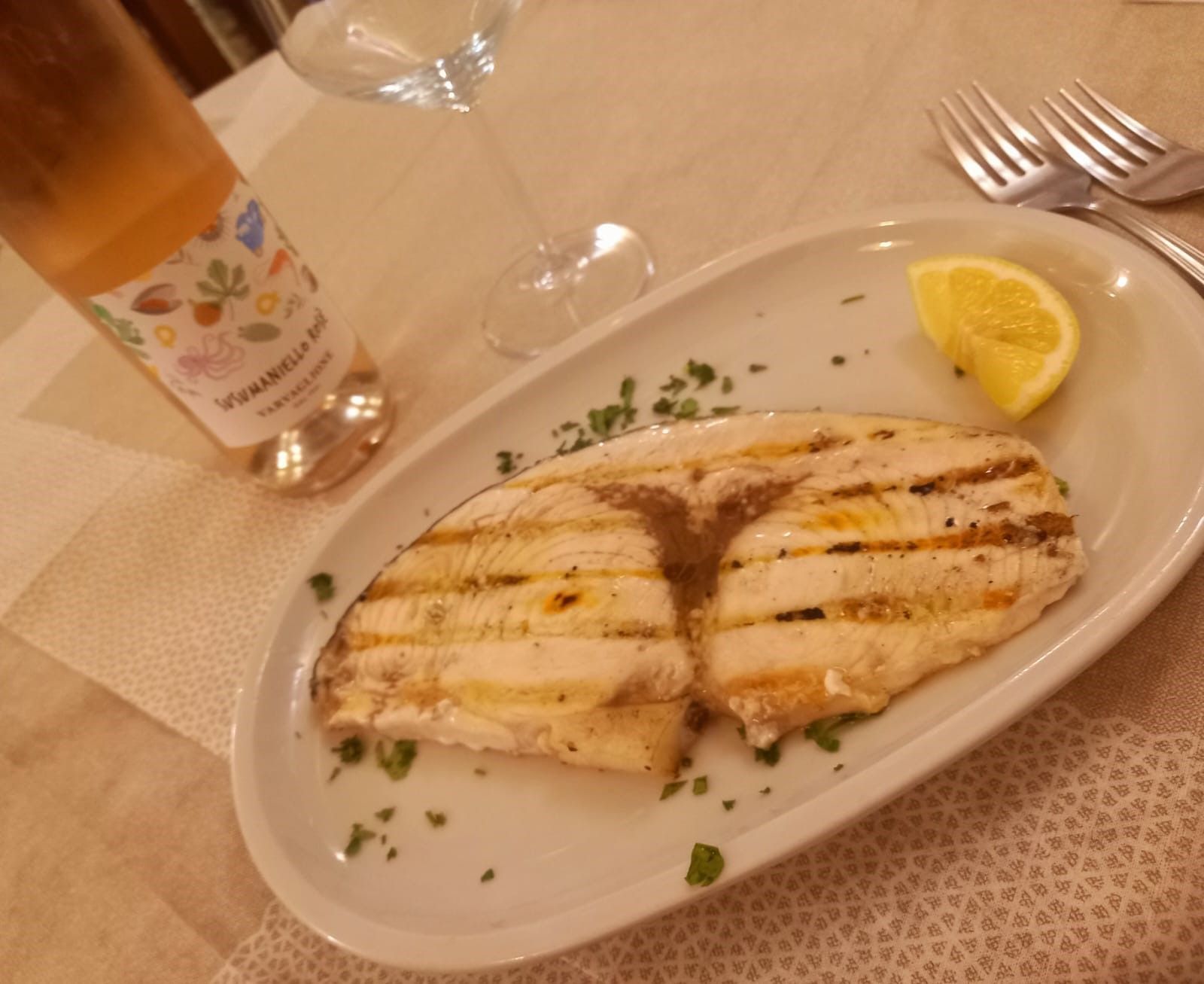 Un piatto di cibo accanto a una bottiglia di vino rosato