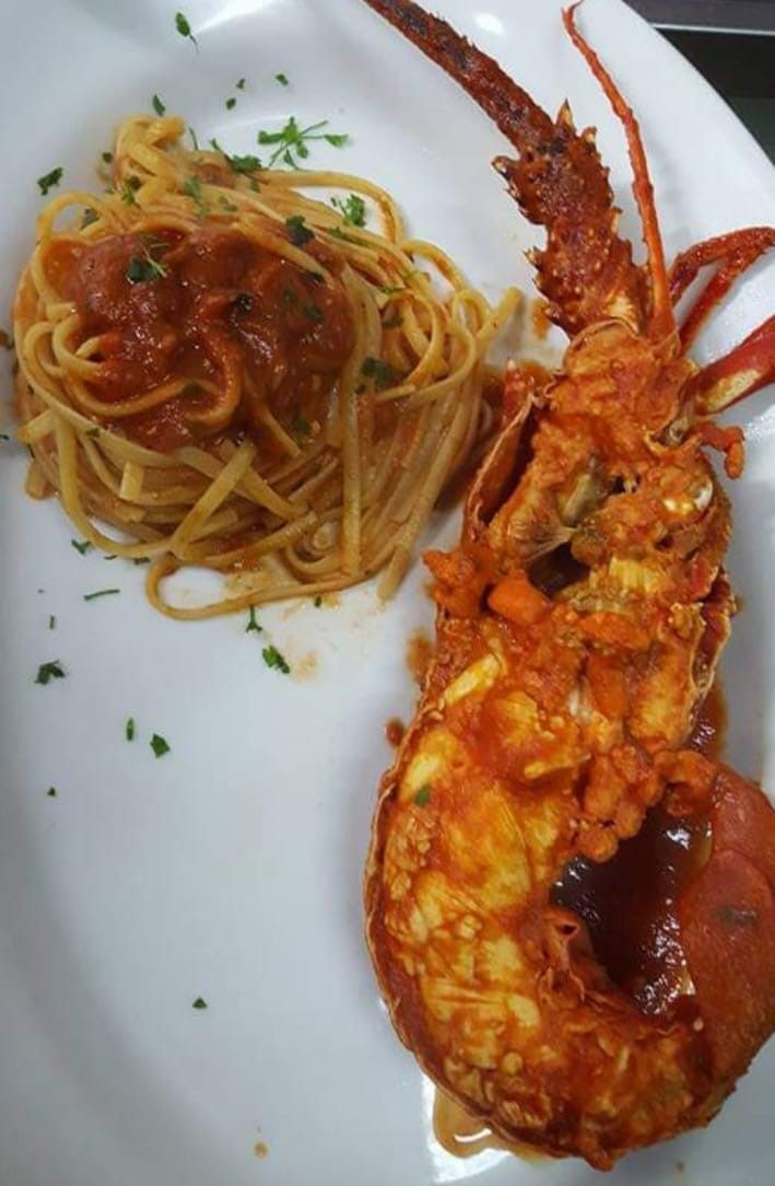 Un piatto bianco con sopra spaghetti e un'aragosta