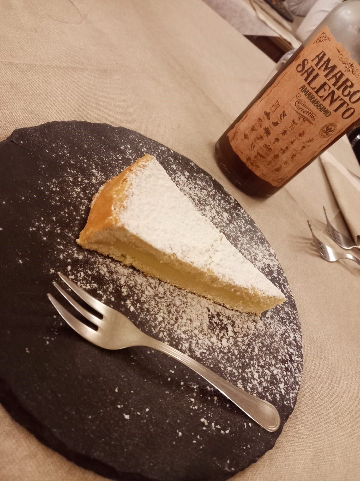 Una bottiglia di amaro salento è accanto a una fetta di torta