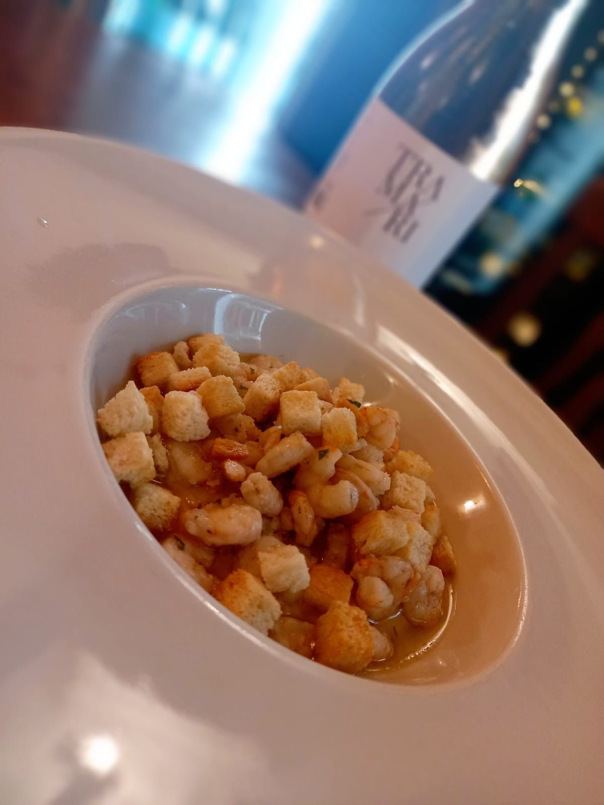 Una ciotola di cibo accanto a una bottiglia di vino Tiga
