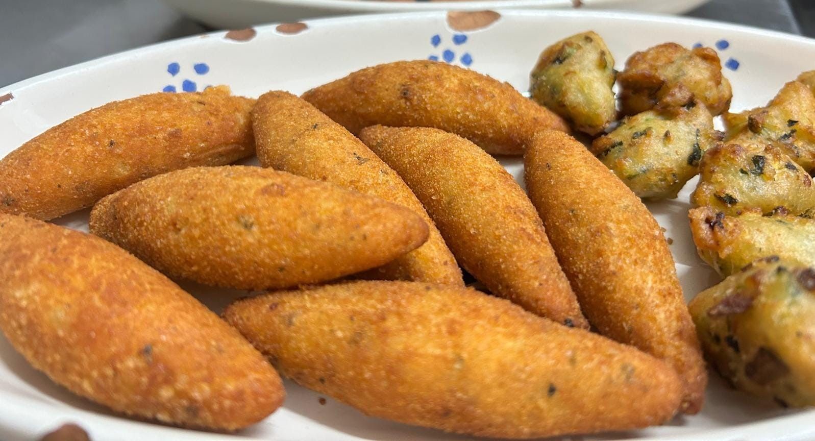Un piatto bianco con sopra del cibo fritto su un tavolo.