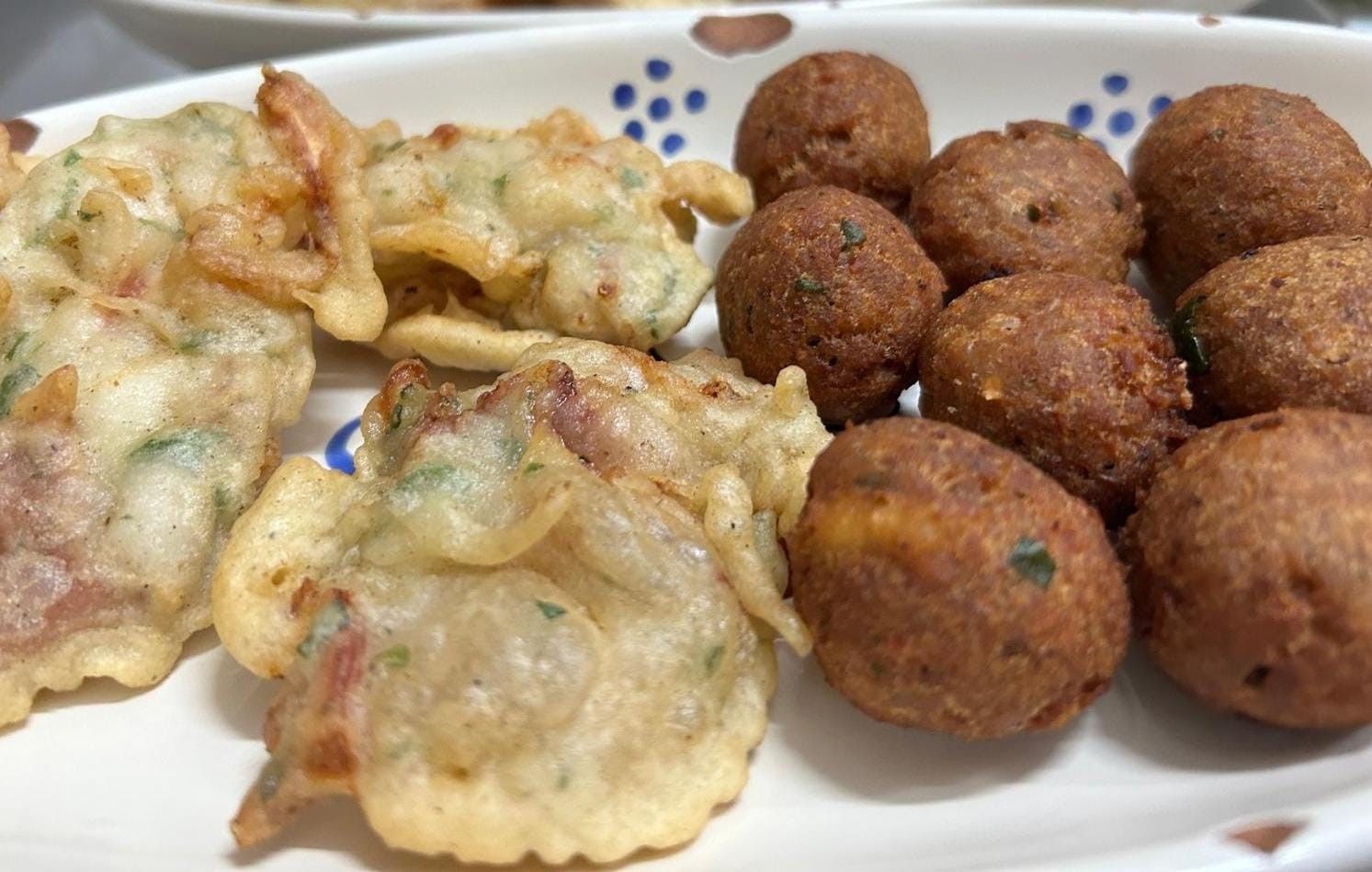 Un piatto di cibo con gamberi fritti e polpette su un tavolo.