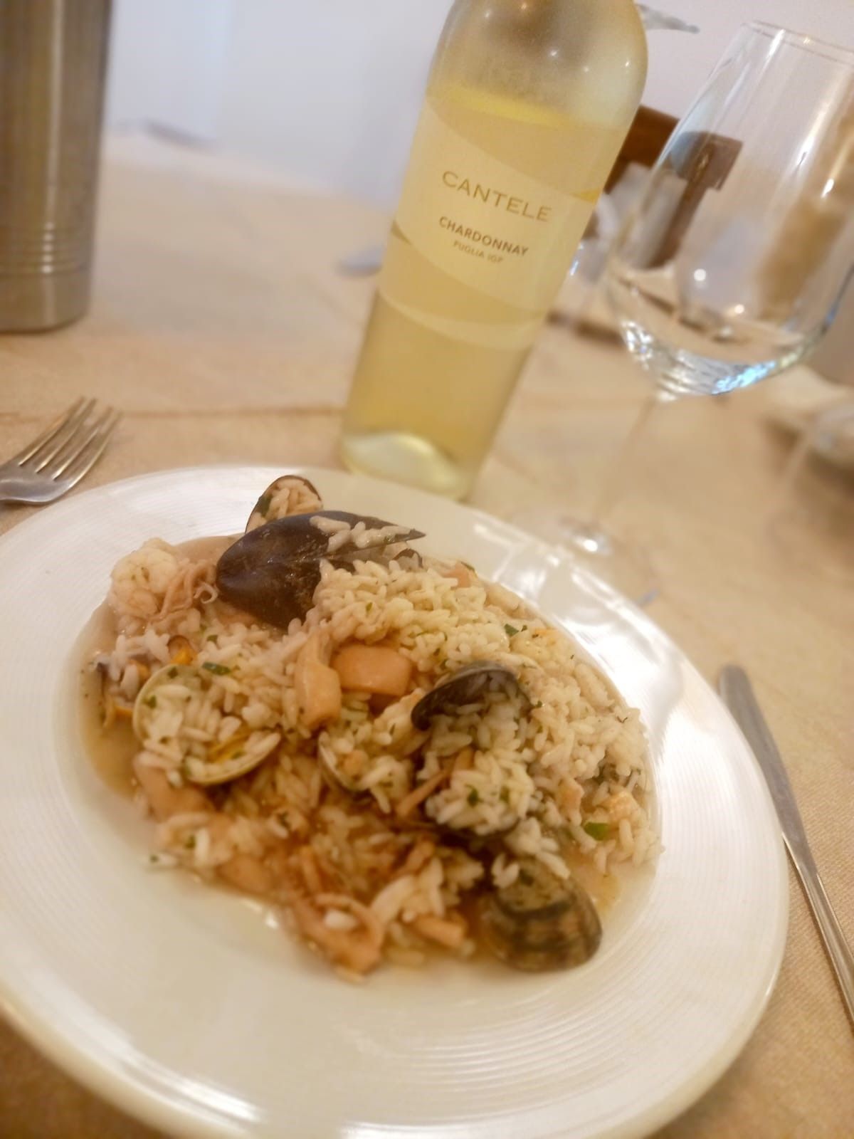 Un piatto di cibo con una bottiglia di vino sullo sfondo