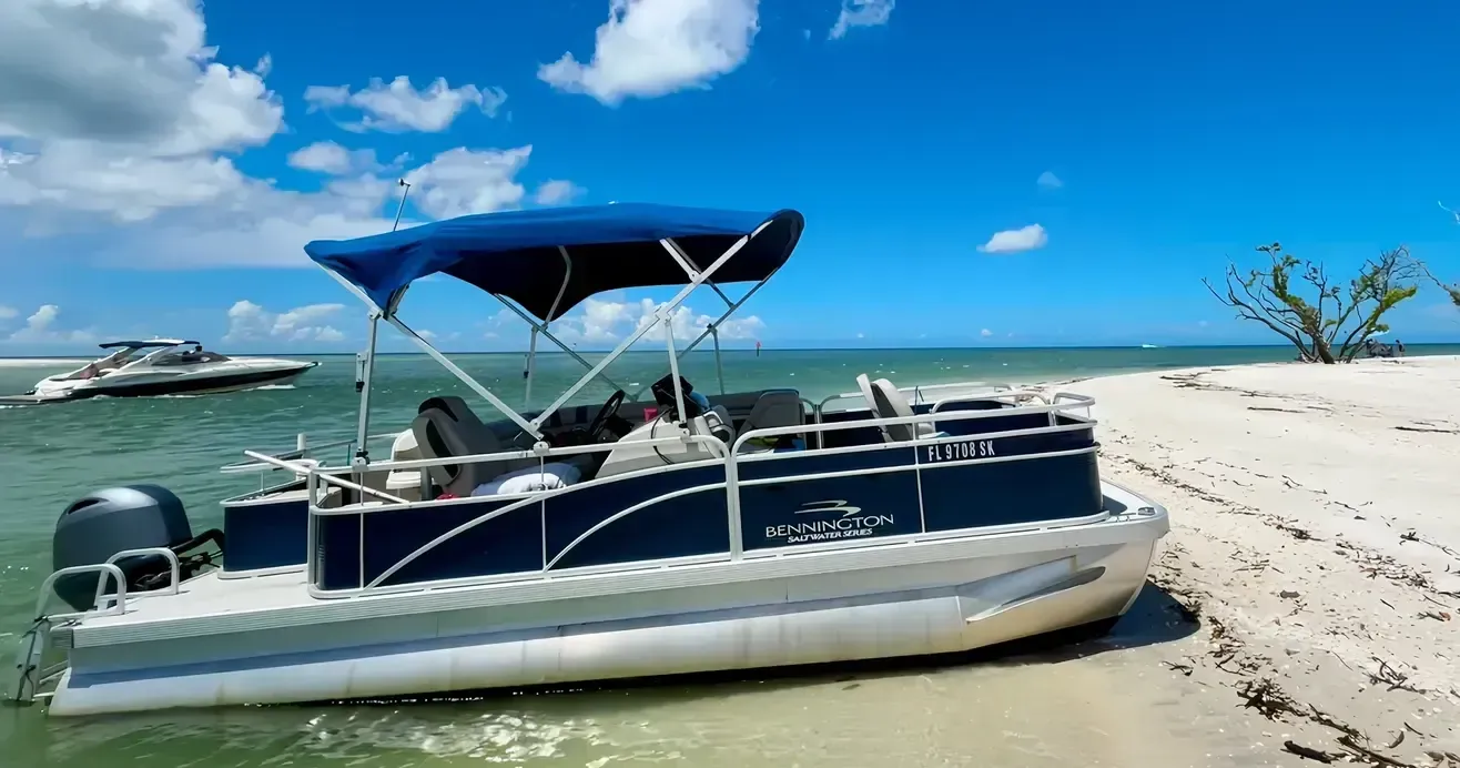 Pontoon boat with blue canopy beached on a sunny tropical shoreline under a clear sky
