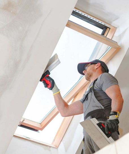 A man is plastering a ceiling with a spatula