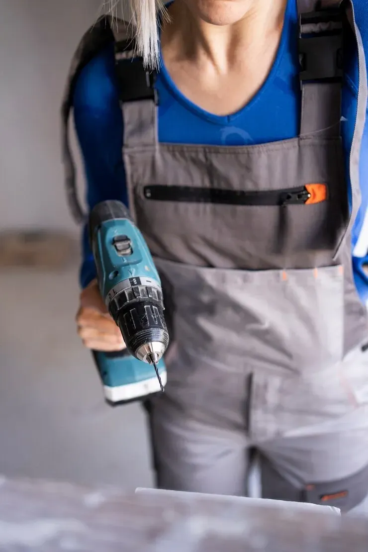 a woman is holding a drill in her hand