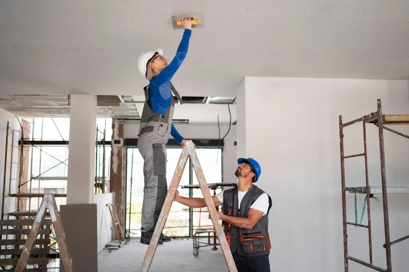 a man is standing on a ladder while a woman is standing on a ladder
