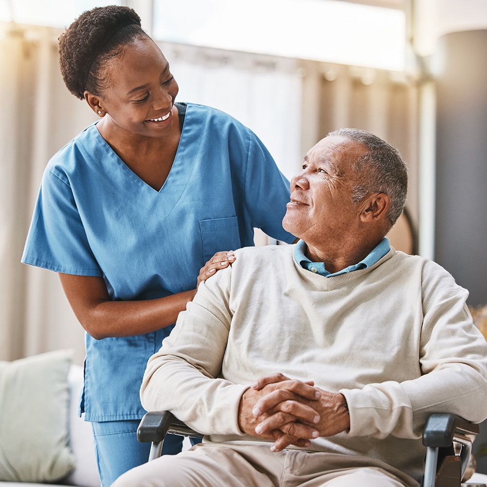A nurse is standing next to an elderly man in a wheelchair.