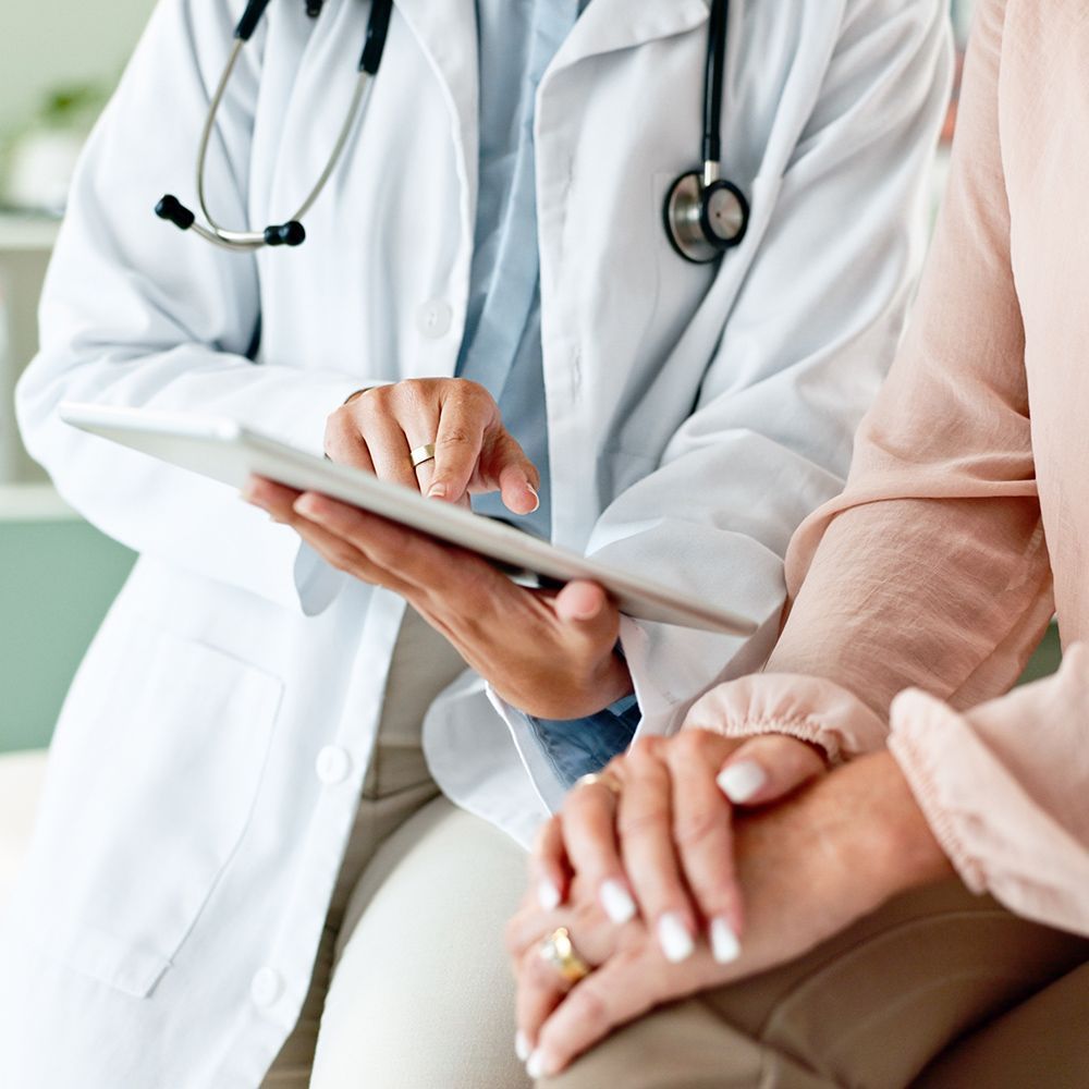 A doctor is holding a tablet and talking to a patient