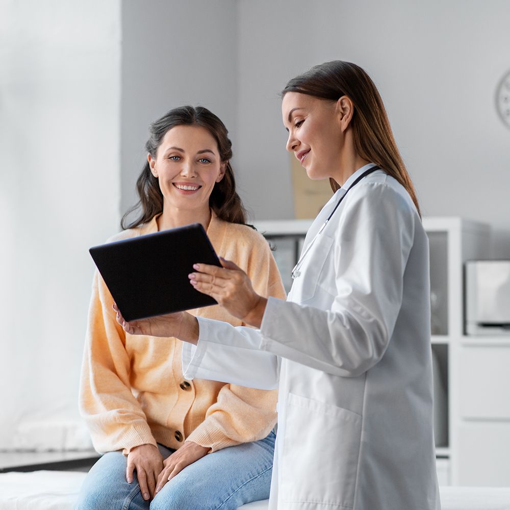 A doctor is talking to a patient while holding a tablet.