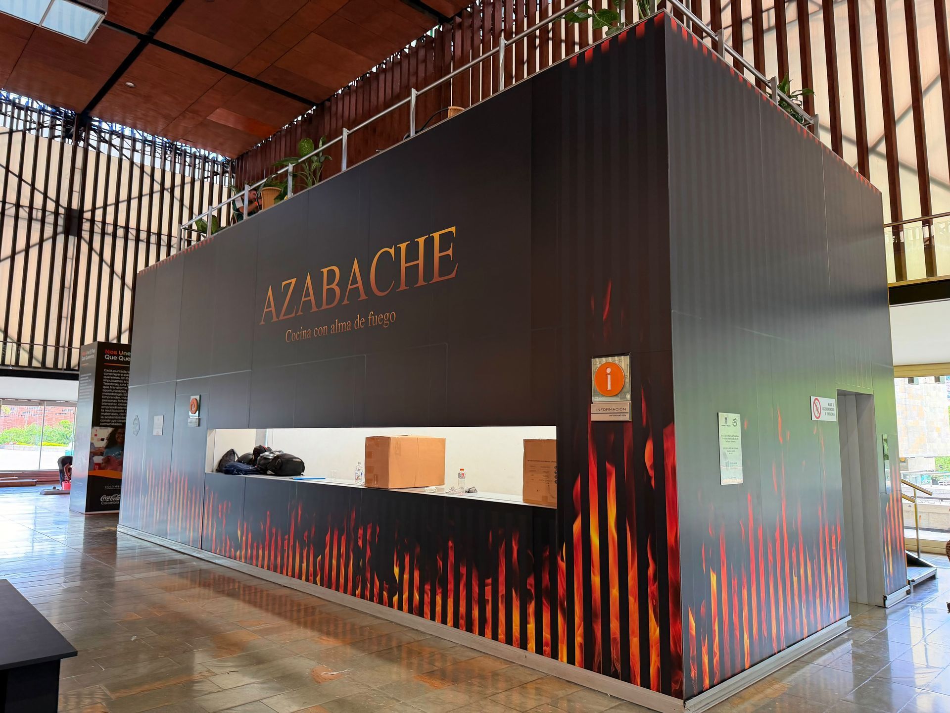 Stand de azabache negro con gráficos de llamas naranjas dentro de un salón con techo de madera.