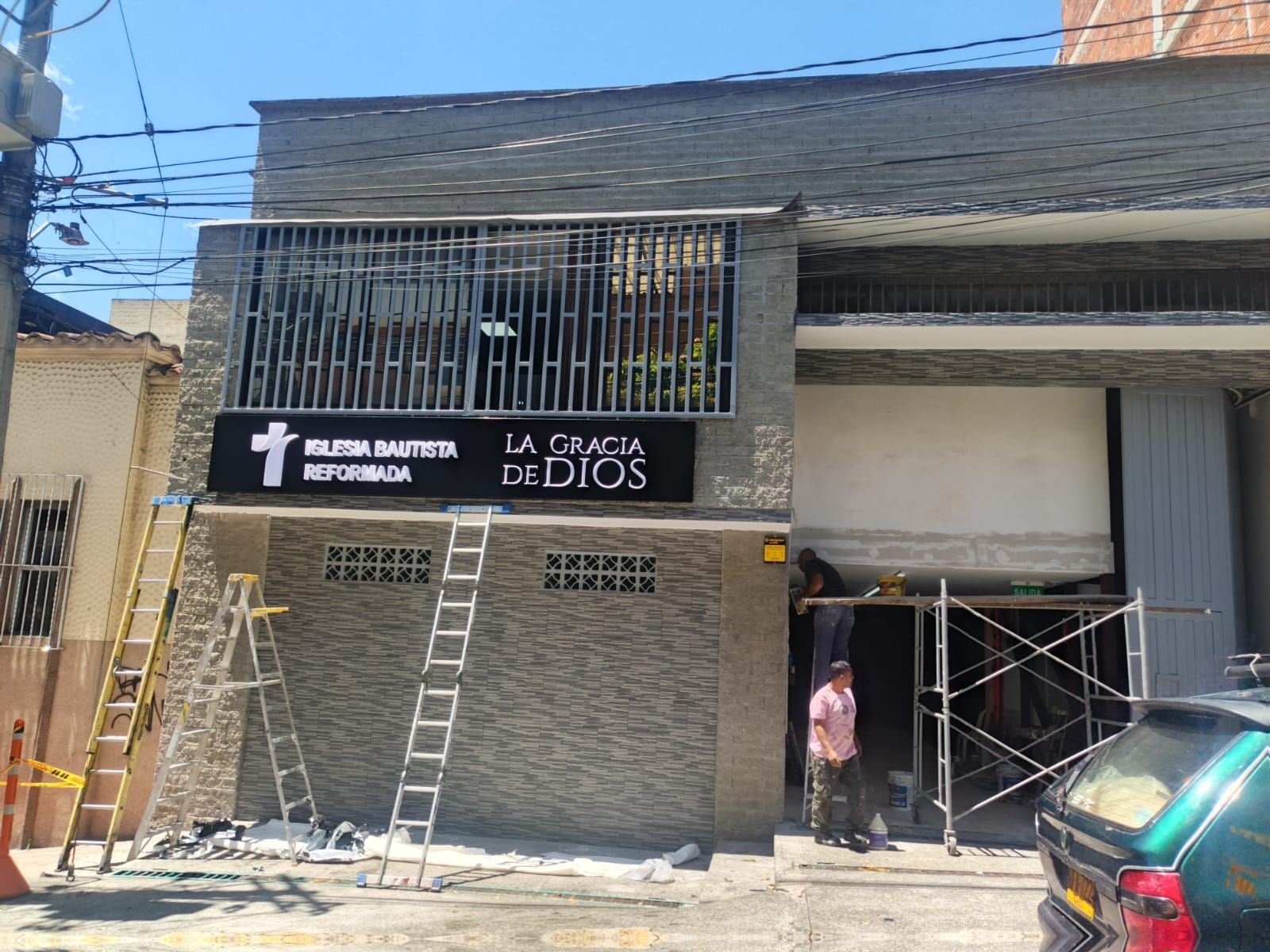Fachada de un edificio con escaleras, andamios y un letrero que dice “La Paz de Dios”.