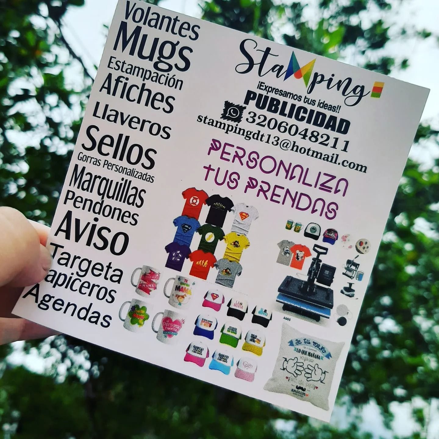 Folleto español hecho a mano que anuncia tazas, camisetas, pegatinas y etiquetas personalizadas, colocado al aire libre.