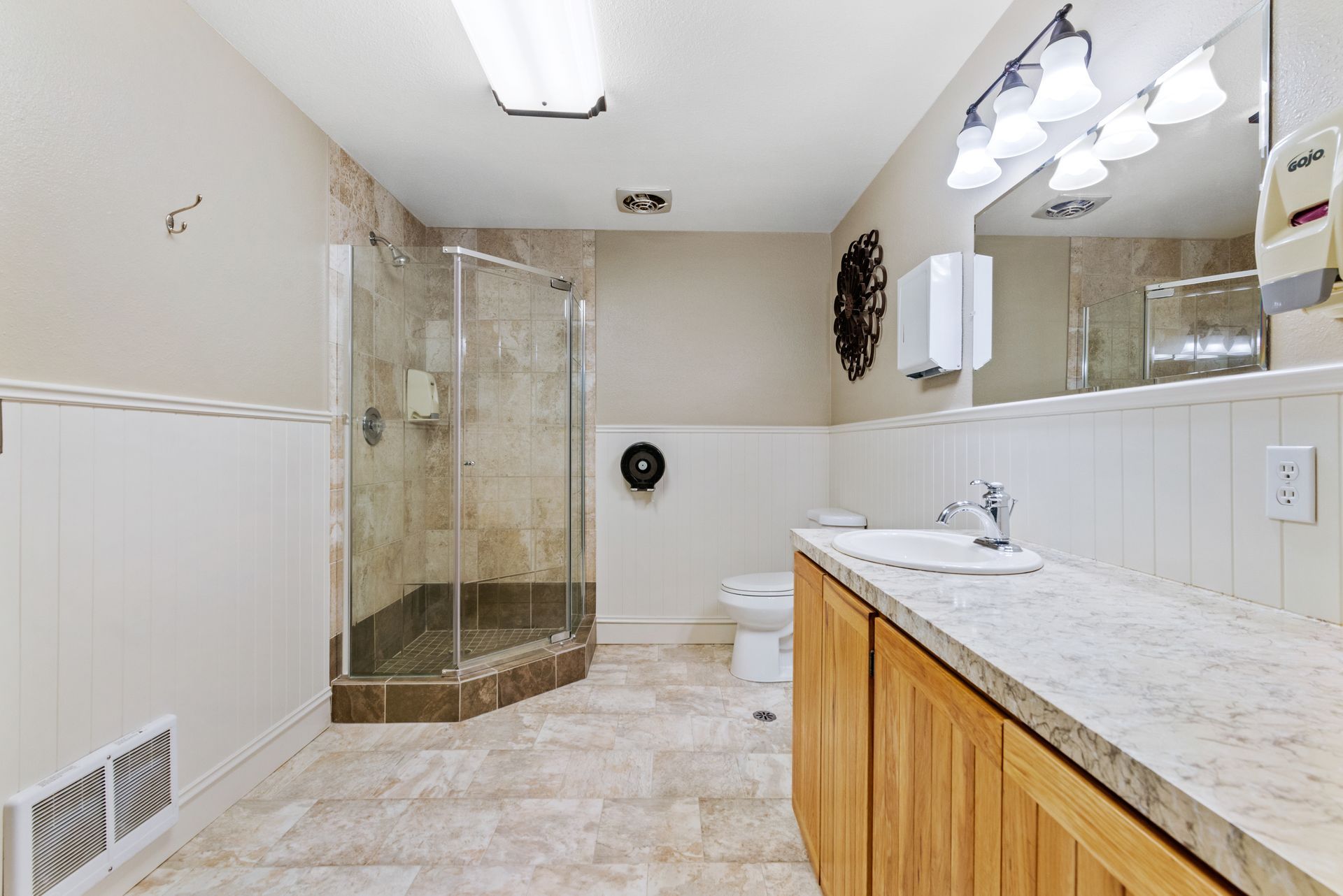 Modern bathroom with glass shower, double sink vanity, tiled floor, and wall mirror