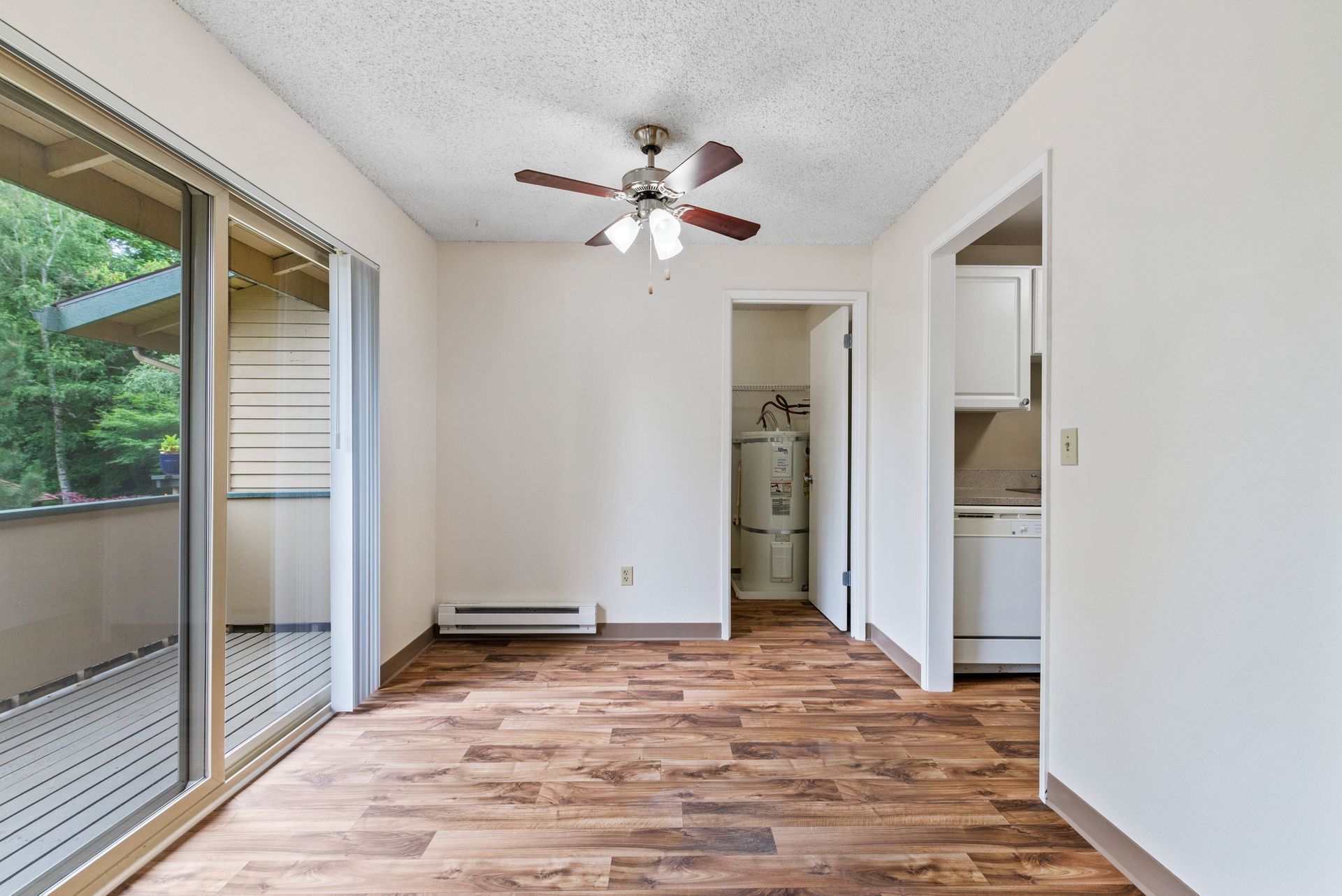 Empty room with wood-look floors, sliding glass doors, ceiling fan, and a small closet doorway