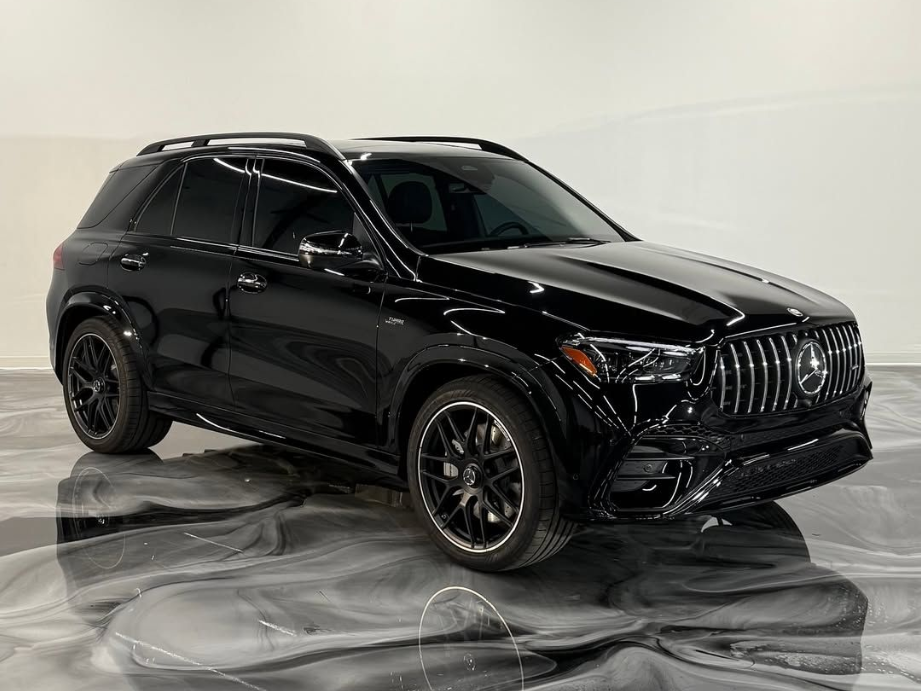 Black Mercedes-AMG GLE SUV on a glossy floor, angled view, showing grille, wheels, and roof rack.