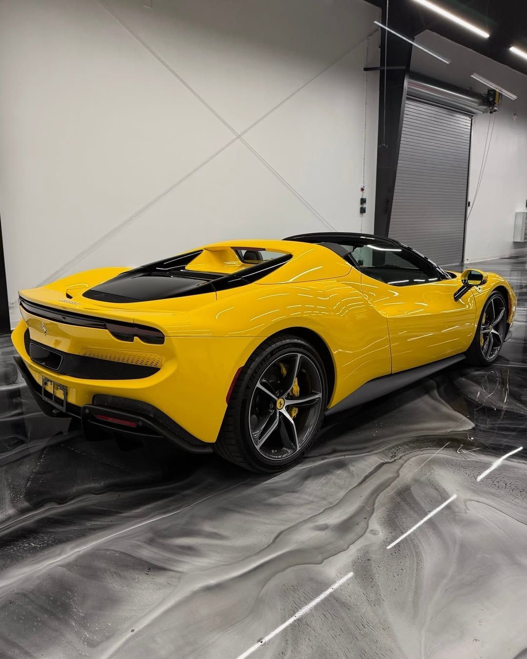 Yellow Ferrari SF90 Spider parked in a garage with a glossy, marbled floor.