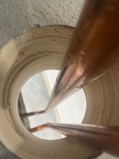 Close-up inside a cardboard tube with two brown wooden sticks and a white background outside the opening
