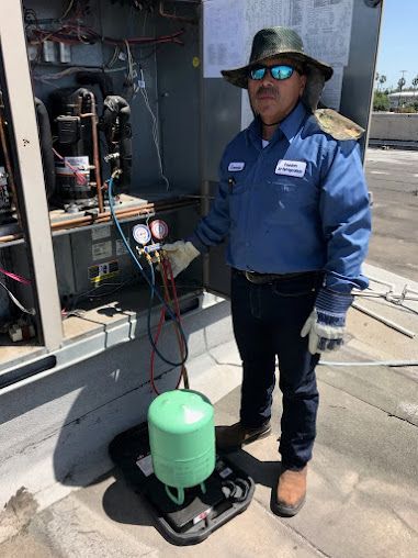 Worker beside green tank and gauges on a rooftop HVAC unit