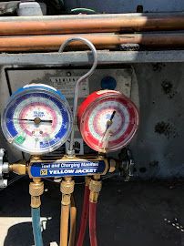 Blue and red HVAC pressure gauges on a yellow charging manifold with hoses attached
