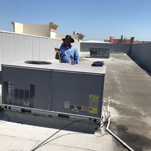 Rooftop HVAC units with a worker inspecting equipment on a sunny day