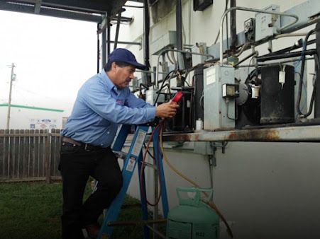 Technician inspecting outdoor electrical equipment with a red handheld device.