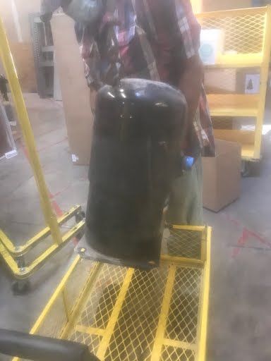 Black trash can on a yellow industrial platform in a warehouse setting