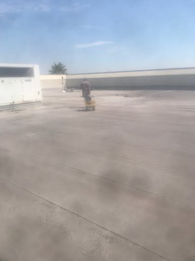 Person standing on a rooftop beside a small yellow cart under a clear blue sky.