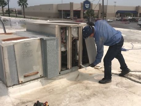 Worker bending over an overturned metal utility box on a sidewalk outdoors