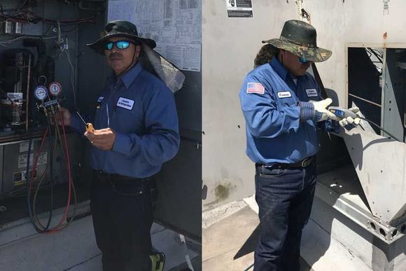 Worker in blue uniform and sun hat using a device beside industrial equipment outdoors