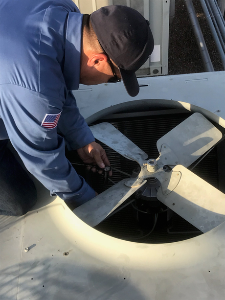 Worker inspecting equipment inside a large industrial fan housing.