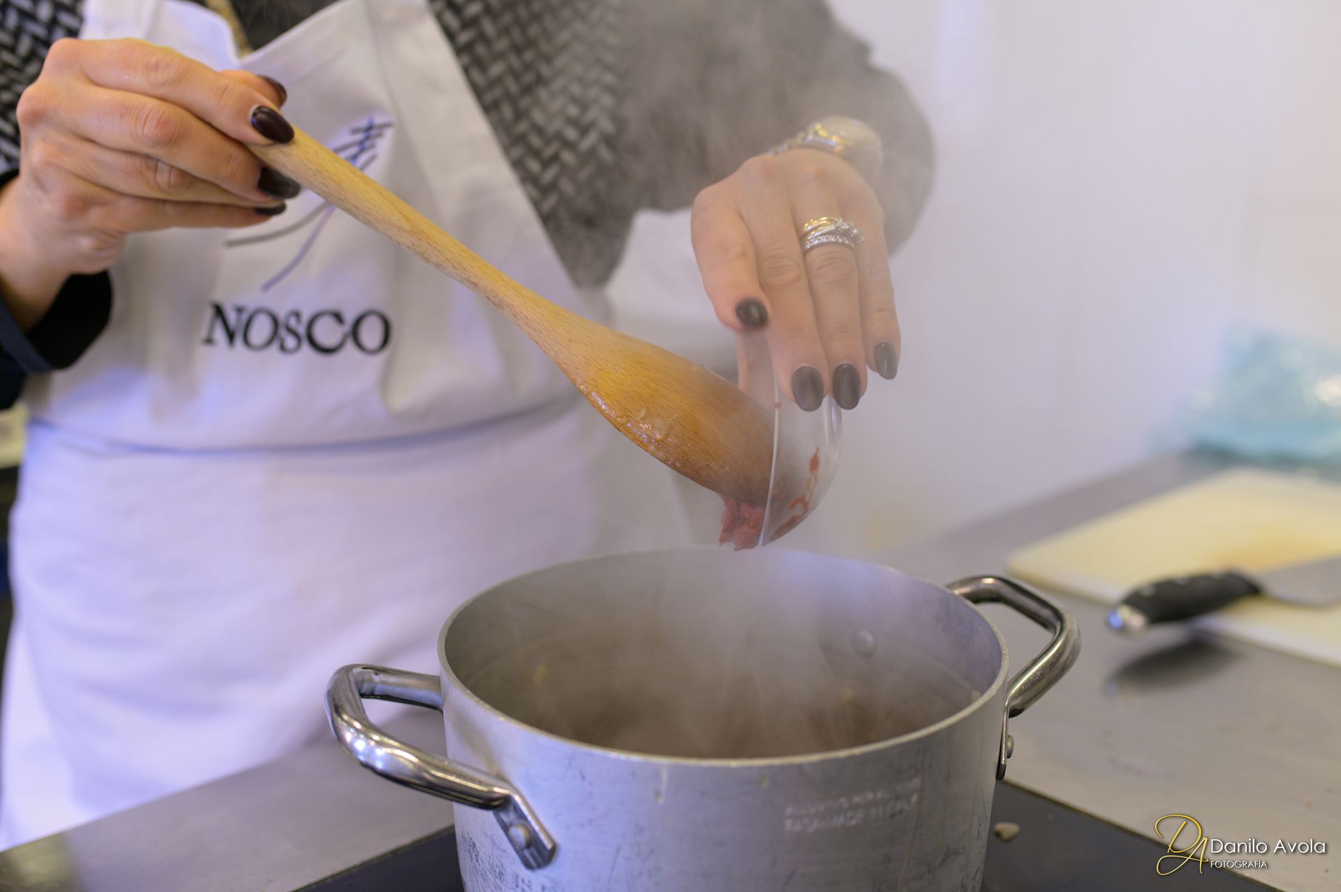 Una donna mescola una pentola di cibo con un cucchiaio di legno - Scuola di Cucina Mediterranea Nosco | Ragusa Ibla | Sicilia