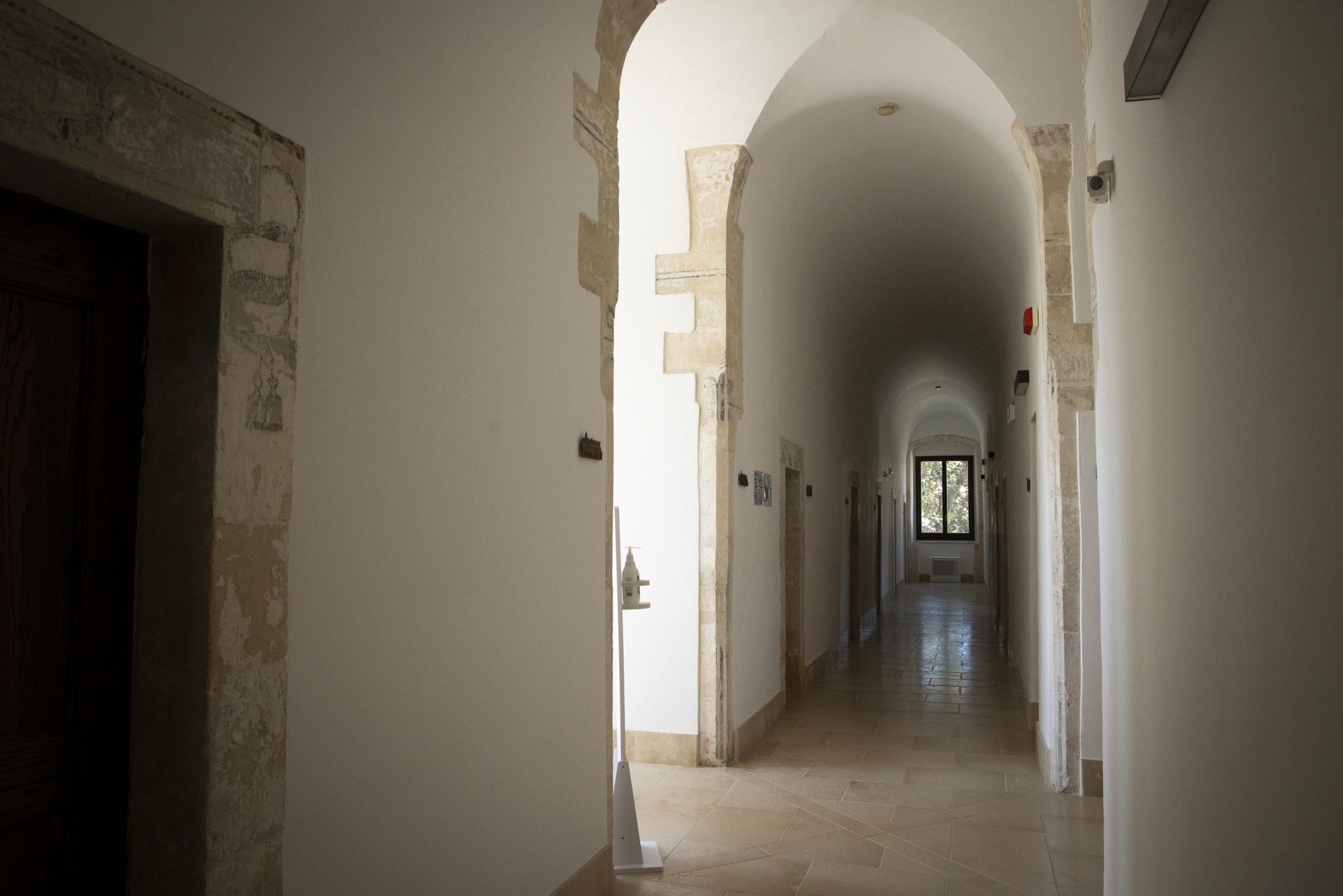 Un lungo corridoio con archi e finestra al centro | Hotel Ritiro con Vista | Antico Convento dei Cappuccini | Ragusa Ibla 