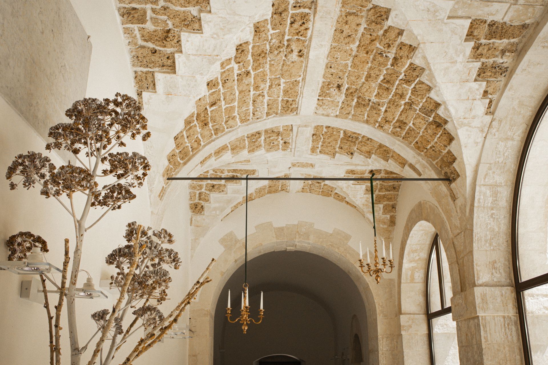 Un corridoio con archi e un lampadario appeso al soffitto | Antico Convento dei Cappuccini | Ragusa Ibla | Sicilia