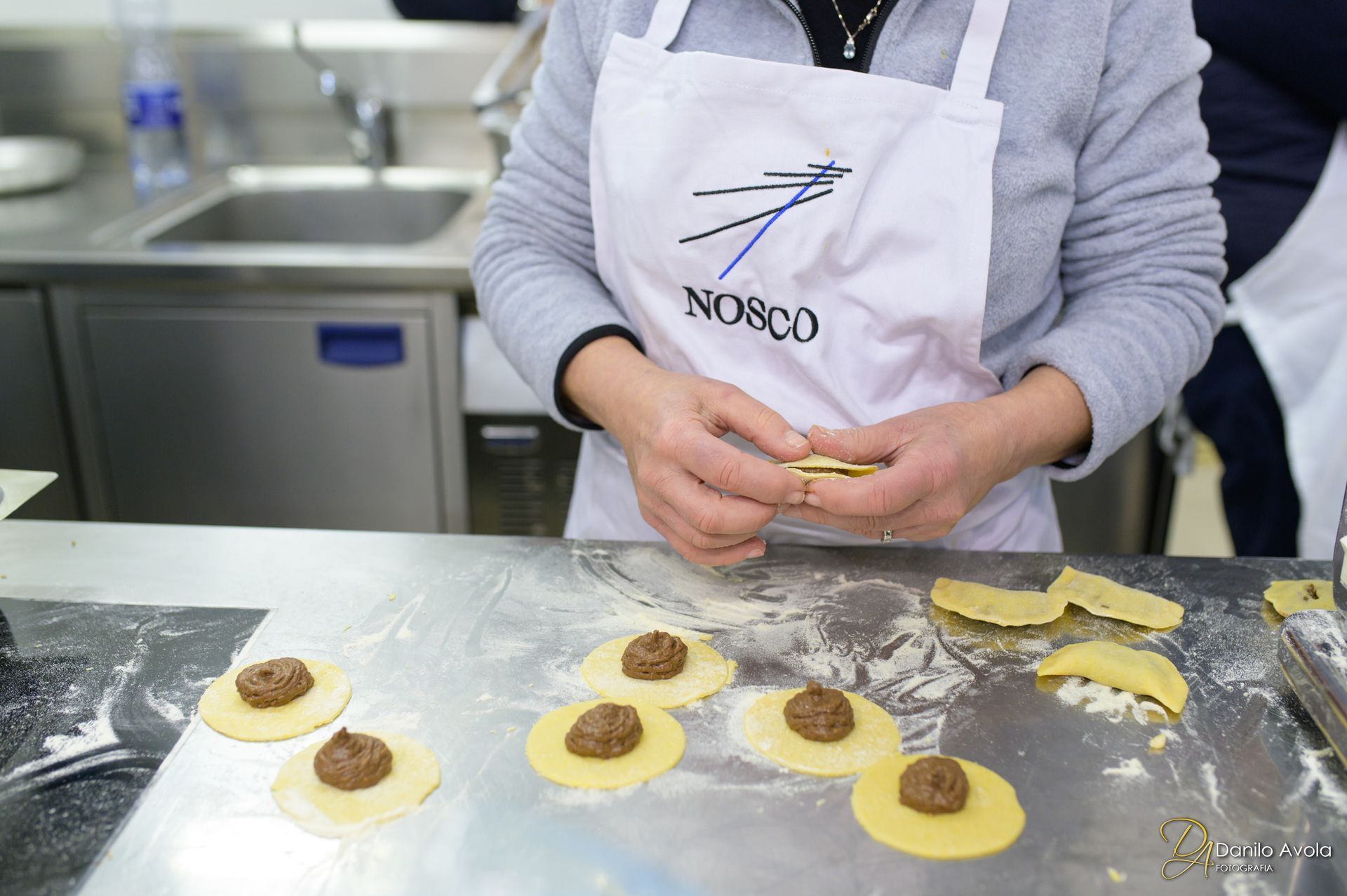 Una persona che indossa un grembiule bianco sta preparando un dolce - Scuola di Cucina Mediterranea Nosco