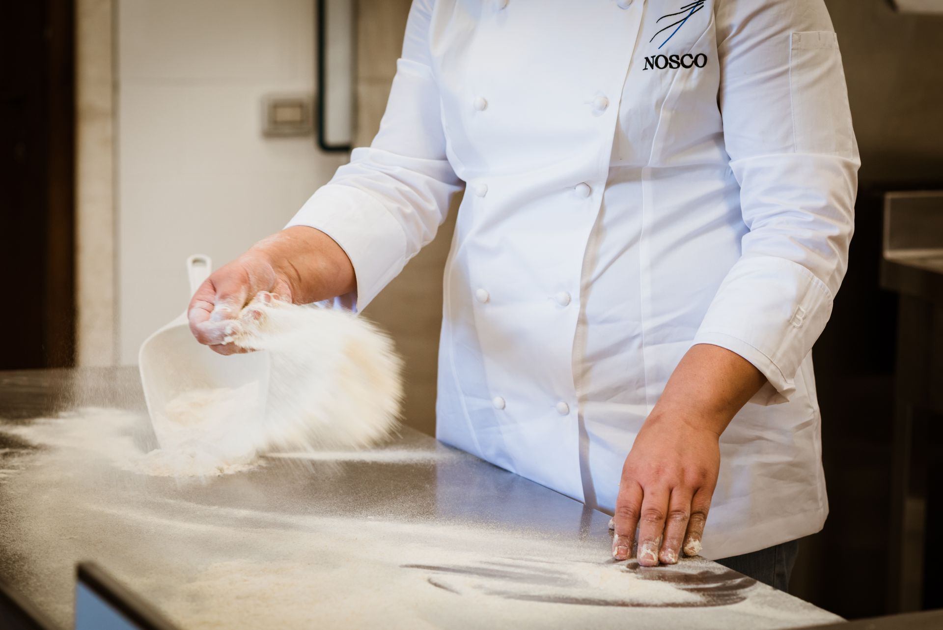 Uno chef versa la farina in una ciotola sul bancone - Scuola di Cucina Mediterranea Nosco | Ragusa Ibla | Sicilia