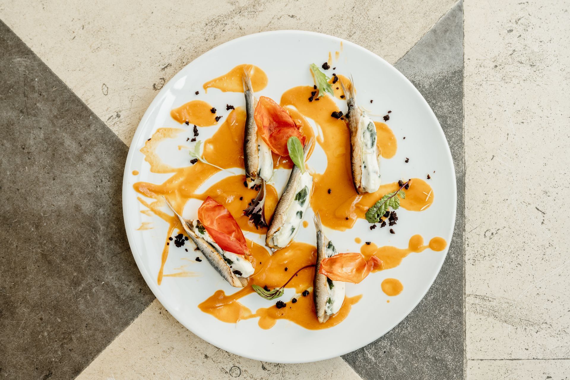 Un piatto bianco con cibo e salsa su un tavolo a scacchi.Osteria dei Frati | Il Cenobio. Antico Convento dei Cappuccini