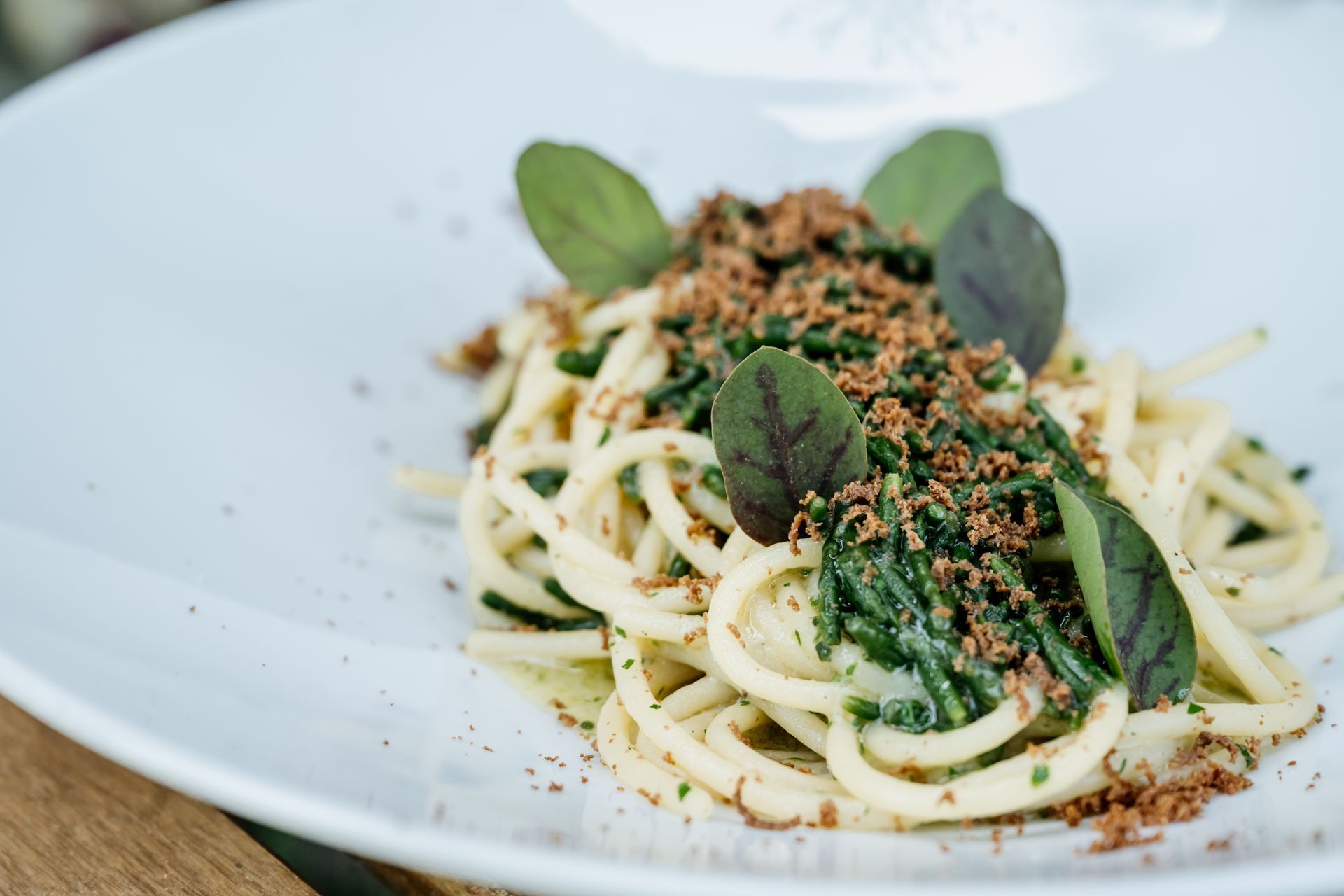 Un piatto con tagliatelle e spinaci su un tavolo di legno. Osteria dei Frati | Il Cenobio. Antico Convento dei Cappuccini