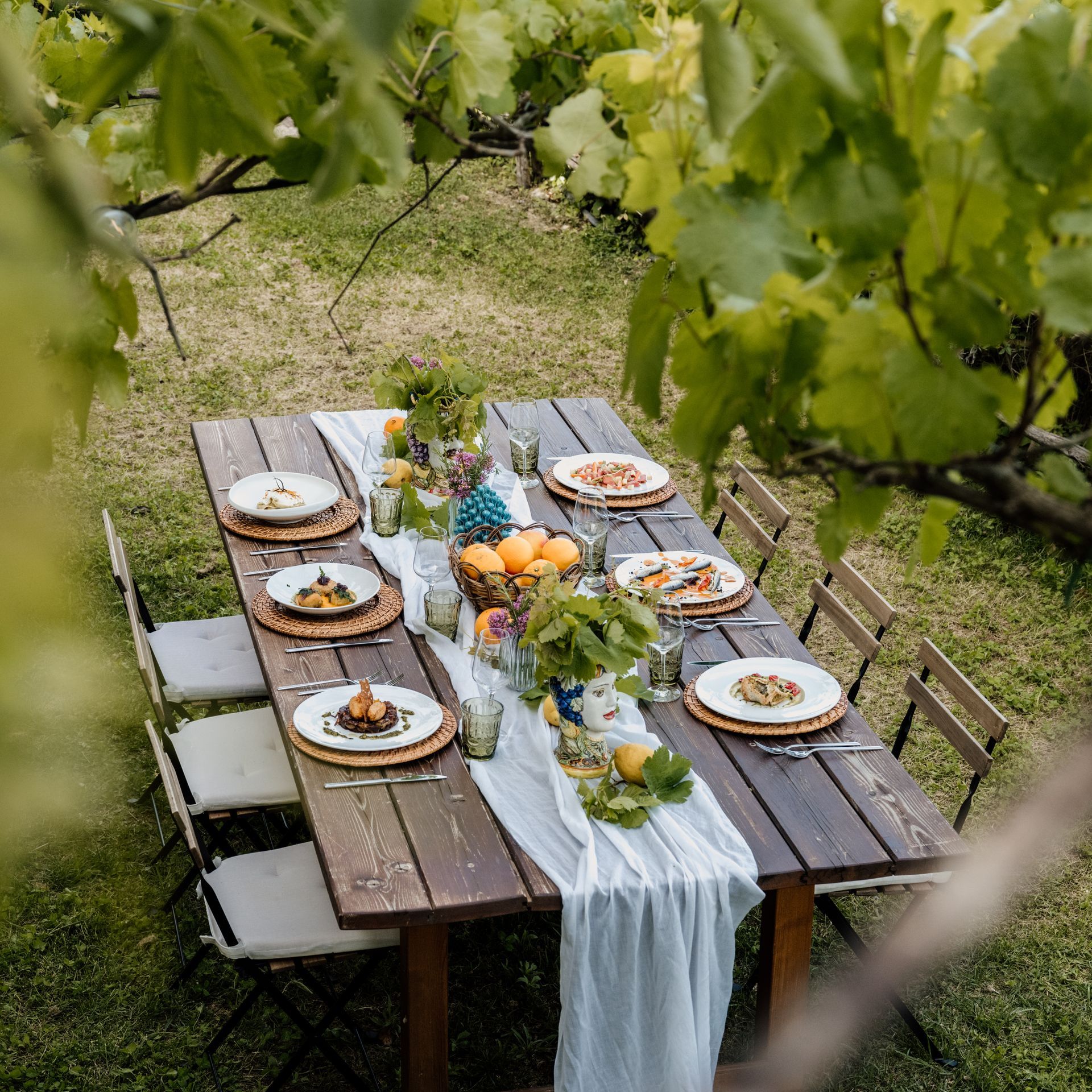 Un lungo tavolo di legno con piatti e bicchieri in un giardino | Aperitivo in vigna all'Antico Convento dei Cappuccini