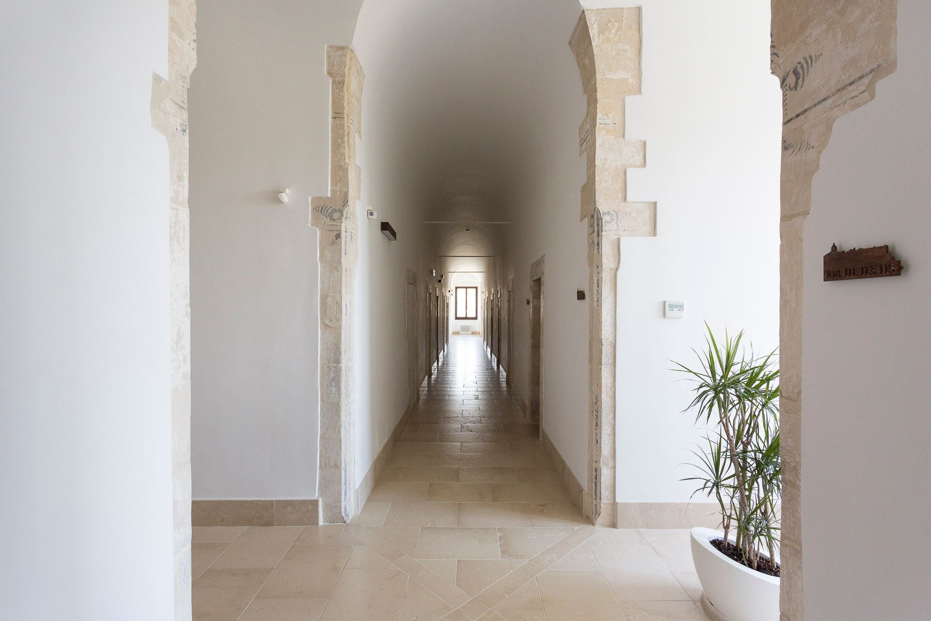 Un lungo corridoio con una pianta al centro. Hotel Ritiro con Vista all'Antico Convento dei Cappuccini di Ragusa Ibla