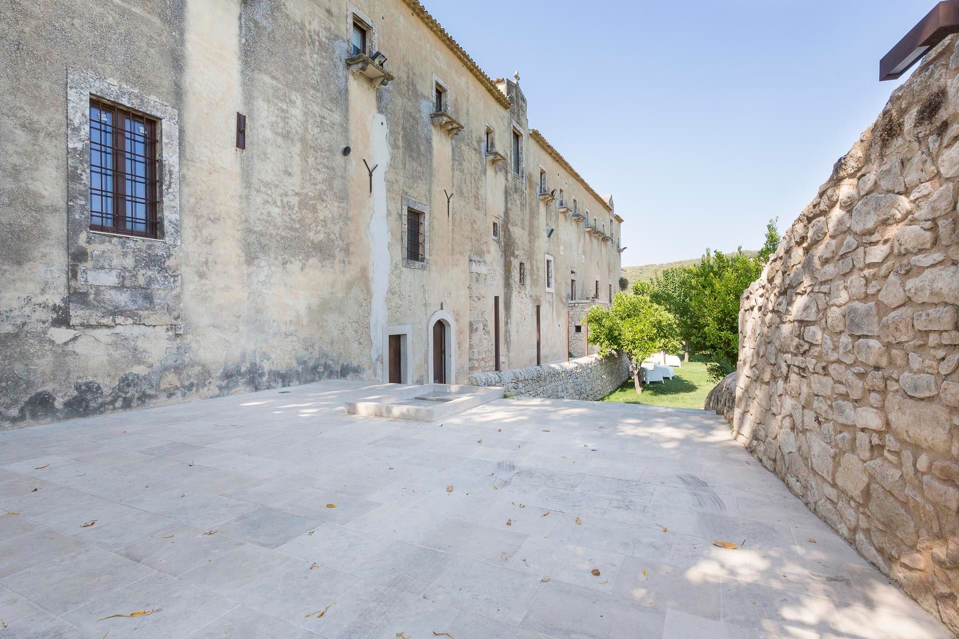 Un grande edificio in pietra con un vialetto di cemento davanti | Antico Convento dei Cappuccini | Ragusa Ibla | Sicilia