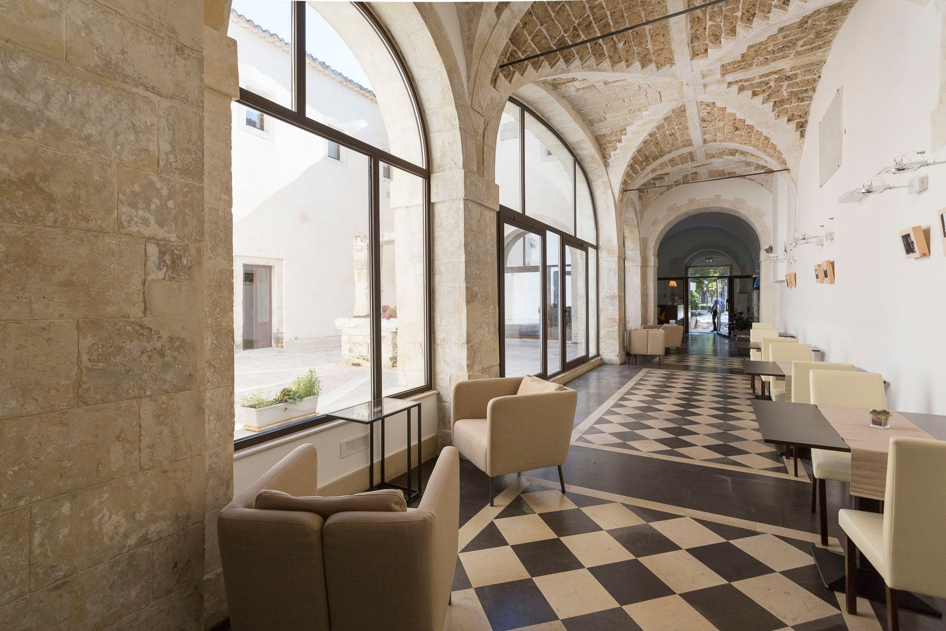 Un lungo corridoio con tavoli e sedie e un pavimento a scacchi | Antico Convento dei Cappuccini | Ragusa Ibla | Sicilia