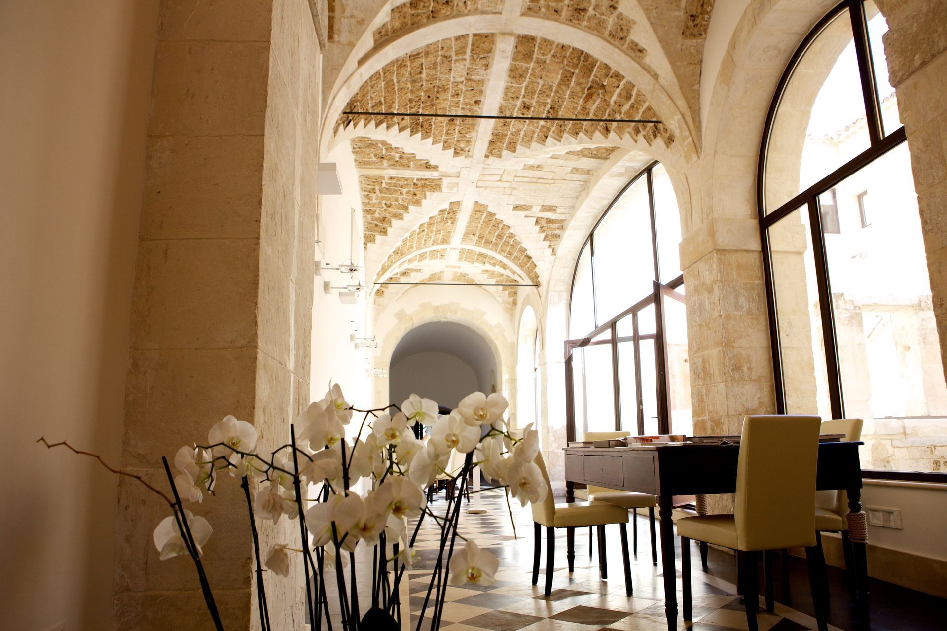 Un corridoio con pianoforte e sedie e un vaso di fiori | Antico Convento dei Cappuccini | Ragusa Ibla | Sicilia
