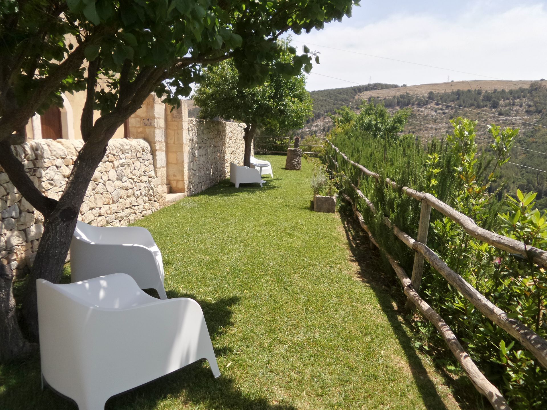 Due sedie bianche sono sedute sotto un albero in una zona erbosa | Antico Convento dei Cappuccini | Ragusa Ibla | Sicilia