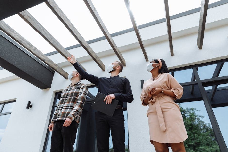 Three people in business attire looking up and pointing under a modern glass pergola outdoors