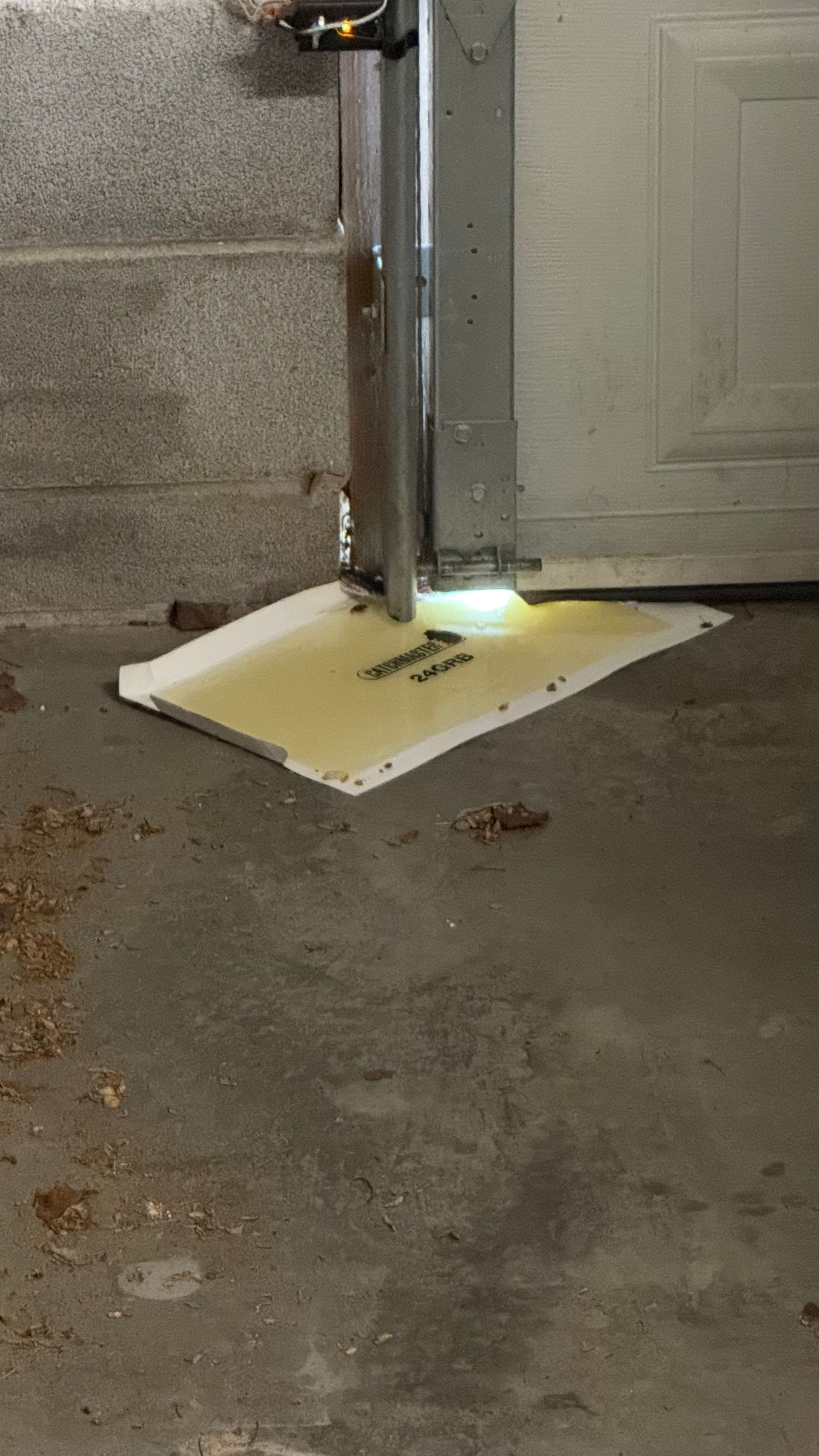 White threshold ramp under a doorway, with a metal support pole and bright light on a concrete floor.