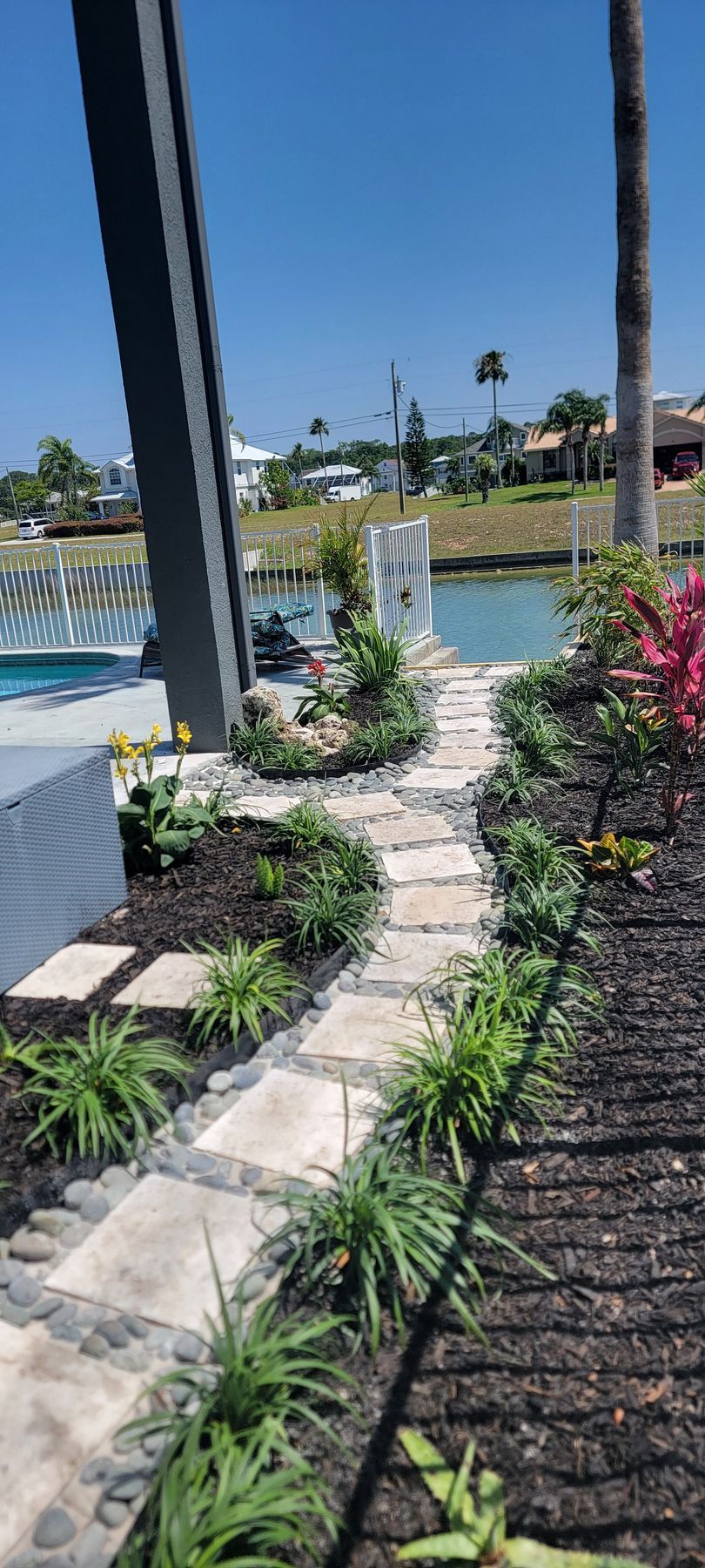 A stone walkway leading to a pool with a waterfall in the background.