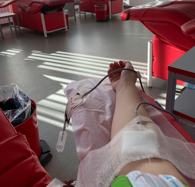 Male practitioner setting up an IV line for a patient on a clinic bed.