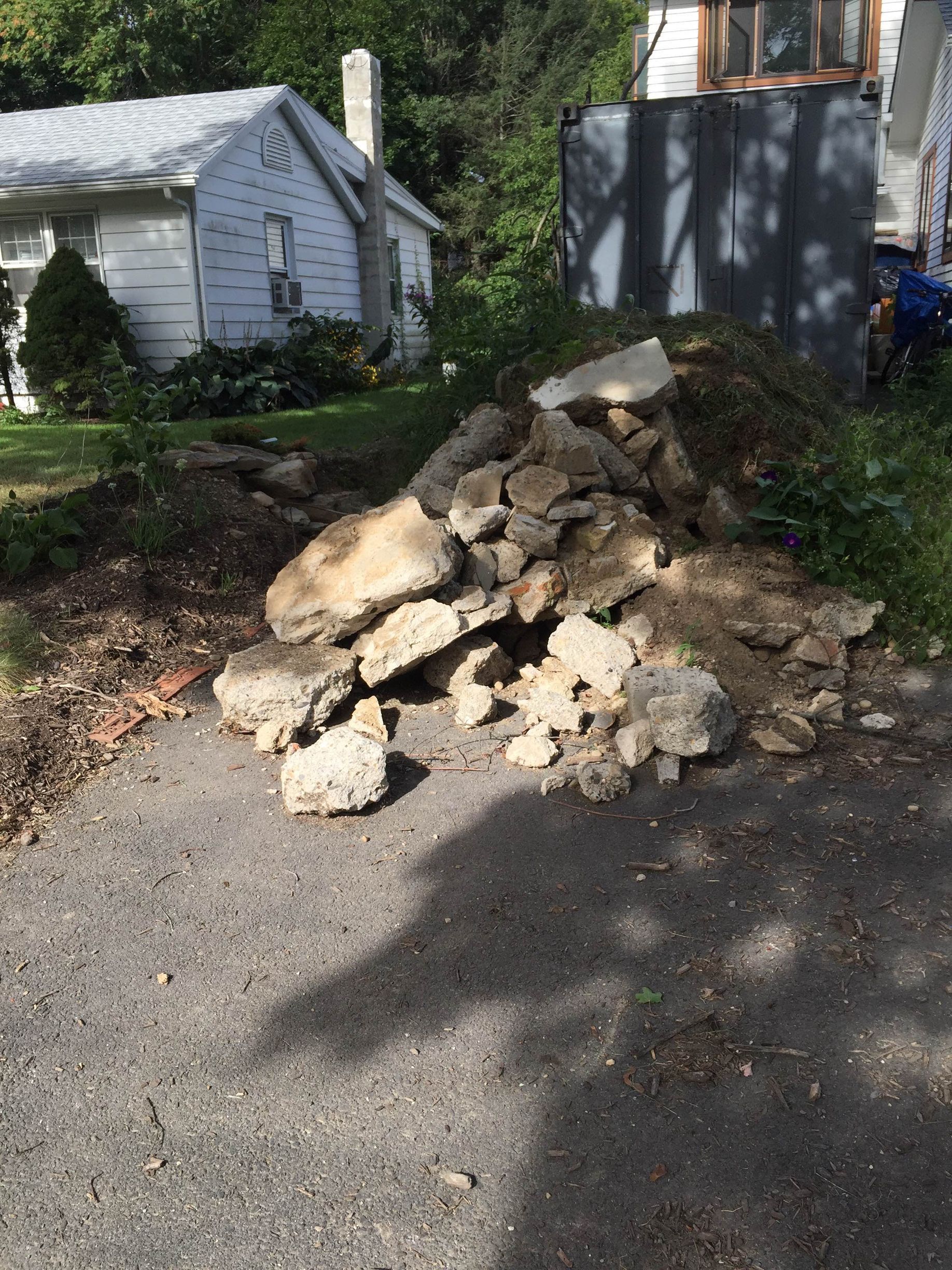 Pile of concrete debris on a paved driveway with a house in the background. Pile of concrete debris on a paved driveway with a house in the background.