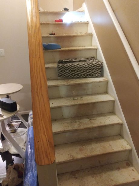 A staircase with a wooden railing and a box on the bottom step